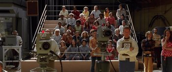 Movie still from “Confessions of a Dangerous Mind” (2002), directed by George Clooney – A group of people sitting in front of a camera; Wide shot, High angle