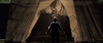 Movie still from “Confessions of a Dangerous Mind” (2002), directed by George Clooney – A man standing in front of a large painting of a woman; Medium shot, Low angle