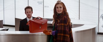 Movie still from “Confessions of a Shopaholic” (2009), directed by P.J. Hogan – A woman in a plaid coat standing in front of a red bag; Medium shot, Over the shoulder angle