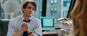 Movie still from “Confessions of a Shopaholic” (2009), directed by P.J. Hogan – A man sitting in front of a computer in front of a window; Close Up shot, Over the shoulder angle