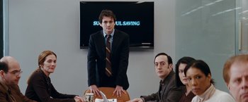 Movie still from “Confessions of a Shopaholic” (2009), directed by P.J. Hogan – A man standing in front of another man in front of a tv; Medium shot, Over the shoulder angle