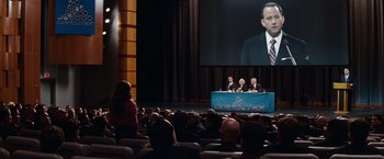 Movie still from “Confessions of a Shopaholic” (2009), directed by P.J. Hogan – A crowd of people watching a presentation on a big screen; Wide shot, High angle