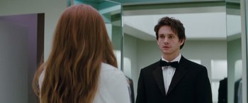 Movie still from “Confessions of a Shopaholic” (2009), directed by P.J. Hogan – A man in a tuxedo looking at a woman in front of a bathroom mirror; Close Up shot, Over the shoulder angle