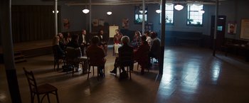 Movie still from “Confessions of a Shopaholic” (2009), directed by P.J. Hogan – A group of people sitting in a circle in a room; Wide shot, High angle