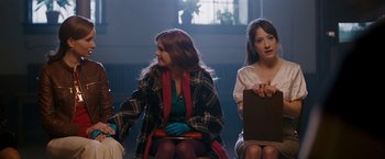 Movie still from “Confessions of a Shopaholic” (2009), directed by P.J. Hogan – A group of people sitting in a room; Medium shot, Over the shoulder angle