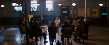 Movie still from “Confessions of a Shopaholic” (2009), directed by P.J. Hogan – A group of people sitting in a circle in front of a window; Wide shot, High angle