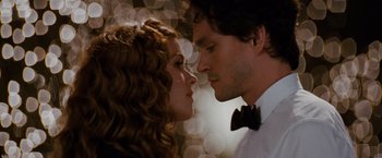 Movie still from “Confessions of a Shopaholic” (2009), directed by P.J. Hogan – A man and a woman face to face in front of a bokeh background; Close Up shot, Over the shoulder angle