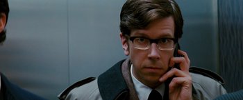 Movie still from “Confessions of a Shopaholic” (2009), directed by P.J. Hogan – A man with glasses is looking at the camera; Close Up shot, Over the shoulder angle