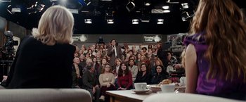 Movie still from “Confessions of a Shopaholic” (2009), directed by P.J. Hogan – A group of people sitting in front of an audience; Wide shot, Over the shoulder angle