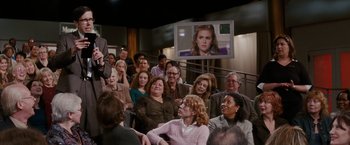 Movie still from “Confessions of a Shopaholic” (2009), directed by P.J. Hogan – A group of people sitting in front of a television; Medium shot, Over the shoulder angle