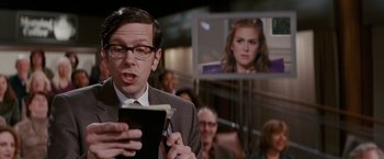 Movie still from “Confessions of a Shopaholic” (2009), directed by P.J. Hogan – A man holding a cell phone in front of a woman; Close Up shot, Over the shoulder angle