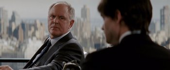 Movie still from “Confessions of a Shopaholic” (2009), directed by P.J. Hogan – A man in a suit and tie sitting next to another man in a suit and tie; Close Up shot, Over the shoulder angle