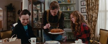 Movie still from “Confessions of a Shopaholic” (2009), directed by P.J. Hogan – A woman cutting a cake on top of a white plate; Medium shot, Over the shoulder angle