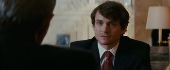 Movie still from “Confessions of a Shopaholic” (2009), directed by P.J. Hogan – A man wearing a suit and tie talking to another man wearing a suit and tie; Close Up shot, Over the shoulder angle