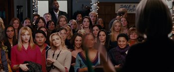 Movie still from “Confessions of a Shopaholic” (2009), directed by P.J. Hogan – A group of people that are standing in a room; Medium shot, Over the shoulder angle