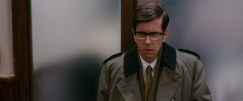 Movie still from “Confessions of a Shopaholic” (2009), directed by P.J. Hogan – A man in a trench coat and tie standing in front of a door; Close Up shot, Over the shoulder angle