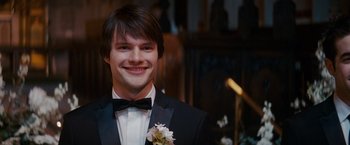 Movie still from “Confessions of a Shopaholic” (2009), directed by P.J. Hogan – A man in a tuxedo smiling for the camera; Close Up shot, Over the shoulder angle