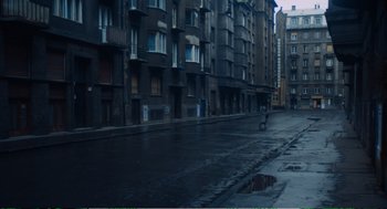 Movie still from “Confidence” (1980), directed by István Szabó – A person riding a bike down a street; Extreme Wide shot, High angle