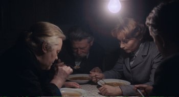 Movie still from “Confidence” (1980), directed by István Szabó – A group of people sitting at a dinner table; Medium shot, High angle