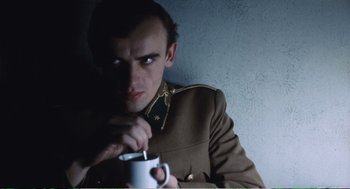 Movie still from “Confidence” (1980), directed by István Szabó – A man in a military uniform holding a coffee mug; Close Up shot, Low angle