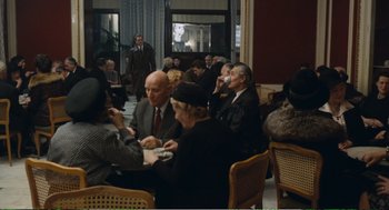 Movie still from “Confidence” (1980), directed by István Szabó – A group of people sitting around a table; Wide shot, High angle