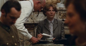 Movie still from “Confidence” (1980), directed by István Szabó – A woman sitting at a table in front of a man; Medium shot, Over the shoulder angle