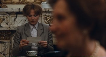 Movie still from “Confidence” (1980), directed by István Szabó – A woman sitting at a table holding a piece of paper; Close Up shot, Over the shoulder angle