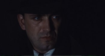 Movie still from “Confidence” (1980), directed by István Szabó – A person wearing a suit and a hat; Close Up shot, Low angle