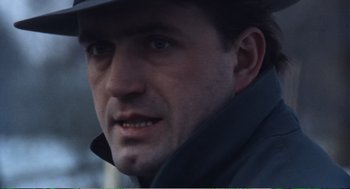 Movie still from “Confidence” (1980), directed by István Szabó – A person wearing a hat and jacket; Close Up shot, Low angle