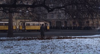 Movie still from “Confidence” (1980), directed by István Szabó – A man standing on the side of a road next to a bus; Extreme Wide shot, High angle
