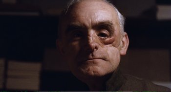 Movie still from “Confidence” (1980), directed by István Szabó – An old man with a shaved head is looking at the camera; Close Up shot, Low angle