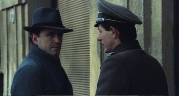 Movie still from “Confidence” (1980), directed by István Szabó – A man in a black hat and a man in a black coat and hat; Close Up shot, Over the shoulder angle