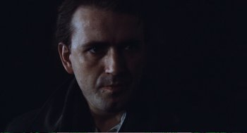 Movie still from “Confidence” (1980), directed by István Szabó – A person wearing a black jacket; Close Up shot, Low angle