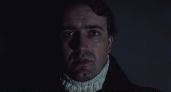 Movie still from “Confidence” (1980), directed by István Szabó – A person wearing a black and white shirt; Close Up shot, Low angle