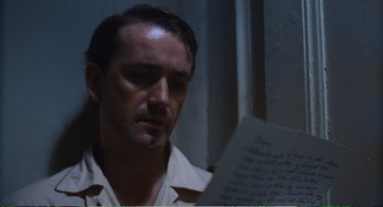 Movie still from “Confidence” (1980), directed by István Szabó – A man looking at a piece of paper in front of a window; Close Up shot, Over the shoulder angle