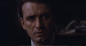 Movie still from “Confidence” (1980), directed by István Szabó – A man's face in a dark room; Close Up shot, Low angle