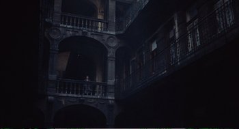 Movie still from “Confidence” (1980), directed by István Szabó – A person standing on a balcony of a building; Extreme Wide shot, High angle