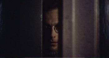 Movie still from “Confidence” (1980), directed by István Szabó – A man with glasses is looking through a window; Close Up shot, Over the shoulder angle