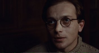 Movie still from “Confidence” (1980), directed by István Szabó – A person wearing round glasses; Close Up shot, Over the shoulder angle