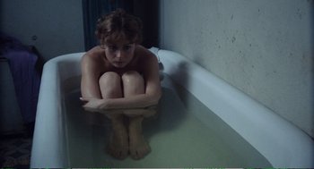 Movie still from “Confidence” (1980), directed by István Szabó – A woman sitting in a bath tub with her legs crossed; Medium shot, Overhead angle