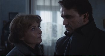 Movie still from “Confidence” (1980), directed by István Szabó – A man and a woman standing next to each other in front of a window; Close Up shot, Low angle
