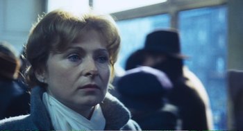 Movie still from “Confidence” (1980), directed by István Szabó – An older woman sitting on a bus with people in the background; Close Up shot, Over the shoulder angle