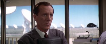 Movie still from “Contact” (1997), directed by Robert Zemeckis – A man in a suit and tie holding a briefcase; Close Up shot, Low angle