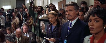 Movie still from “Contact” (1997), directed by Robert Zemeckis – A group of people standing in front of a television; Medium shot, Low angle
