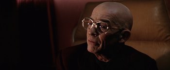 Movie still from “Contact” (1997), directed by Robert Zemeckis – An old man wearing glasses and sitting in a chair; Close Up shot, Low angle