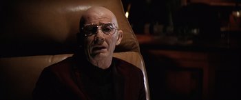 Movie still from “Contact” (1997), directed by Robert Zemeckis – An older man with glasses sitting in a chair; Close Up shot, Low angle