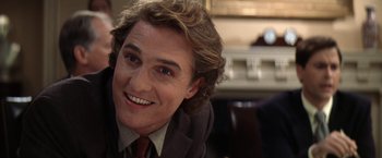 Movie still from “Contact” (1997), directed by Robert Zemeckis – A person wearing a suit and tie smiling; Close Up shot, Over the shoulder angle