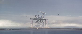 Movie still from “Contact” (1997), directed by Robert Zemeckis – An image of an island with a giant object in the middle of it; Extreme Wide shot, High angle