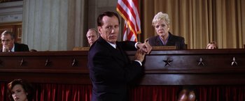 Movie still from “Contact” (1997), directed by Robert Zemeckis – A man in a suit and tie standing in front of a judge; Medium shot, Low angle