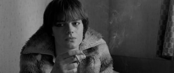 Movie still from “Control” (2007), directed by Anton Corbijn – A young man smoking a cigarette while wearing a fur coat; Close Up shot, High angle